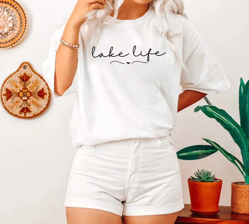 May include: White t-shirt with the text "lake life" in black cursive writing.