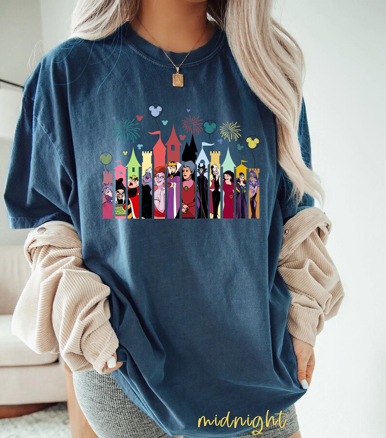 Puede incluir: Camiseta azul marino con un gr&aacute;fico colorido de villanos de Disney frente a un castillo, con fuegos artificiales y siluetas de Mickey Mouse. La palabra "midnight" est&aacute; impresa en oro en la parte inferior.