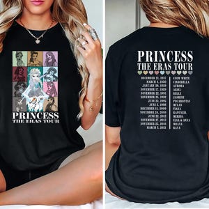May include: Black t-shirt with a graphic of Disney princesses and the text "Princess The Eras Tour". The back of the shirt has a list of princesses and their corresponding movie release dates.