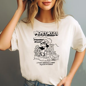 K&ouml;nnte beinhalten: Wei&szlig;es T-Shirt mit einer Schwarzwei&szlig;-Illustration von Mickey Mouse als Dampfschiffkapit&auml;n. Der Text auf dem Shirt lautet "Mickey Mouse Sound Cartoon 'Steamboat Willie' A Walt Disney Comic by Ub Iwerks."