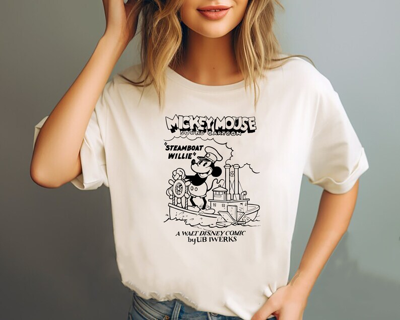 K&ouml;nnte beinhalten: Wei&szlig;es T-Shirt mit einer Schwarzwei&szlig;-Illustration von Mickey Mouse als Dampfschiffkapit&auml;n. Der Text auf dem Shirt lautet "Mickey Mouse Sound Cartoon 'Steamboat Willie' A Walt Disney Comic by Ub Iwerks."