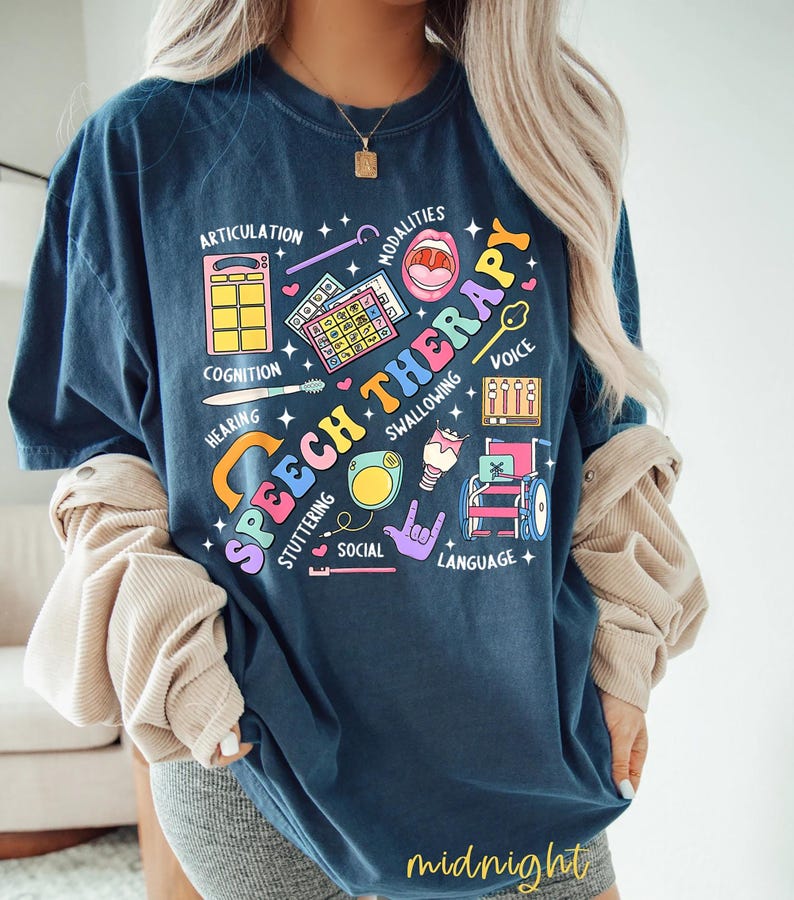 May include: A navy blue t-shirt with a colorful graphic design that says "Speech Therapy". The graphic includes illustrations of various speech therapy tools and concepts, such as a mouth, a microphone, a wheelchair, and a sign language hand gesture. The text around the graphic includes words like "articulation", "cognition", "hearing", "voice", "swallowing", "stuttering", "social", and "language".