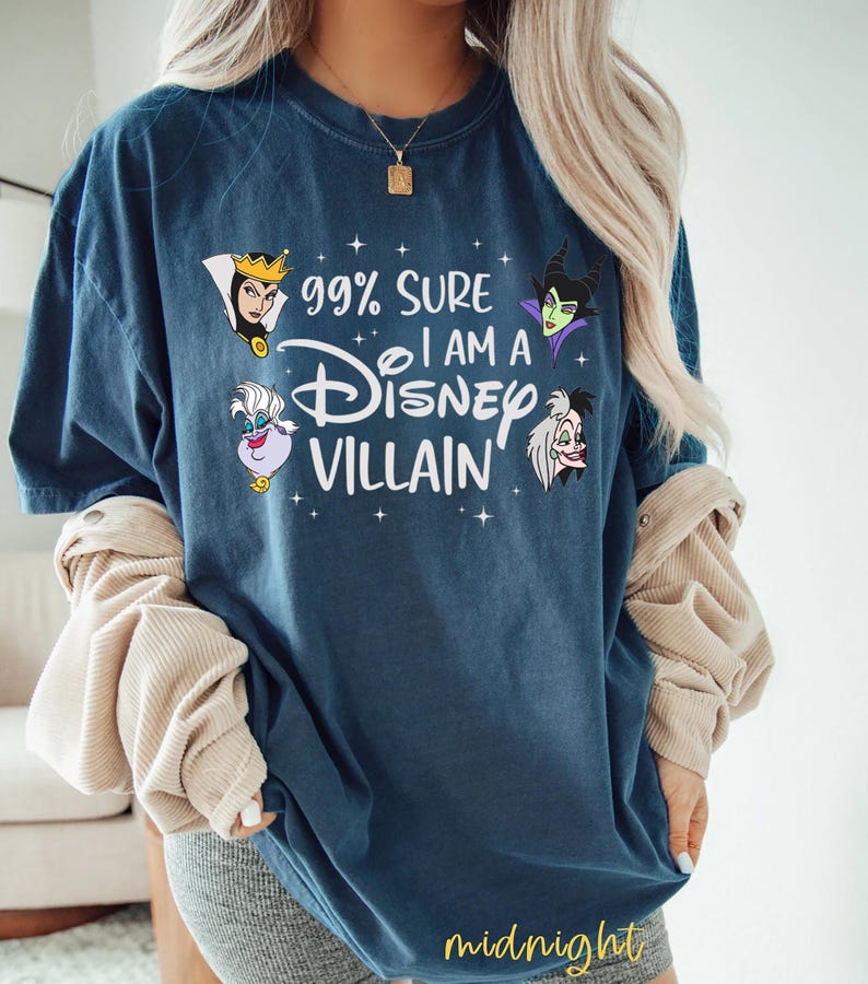 以下が含まれることがあります： 「99% Sure I am a Disney Villain」の文字とディズニーヴィランズのイラストがプリントされたネイビーブルーのTシャツ。Tシャツは濃い青色で、ゆったりとしたフィット感です。