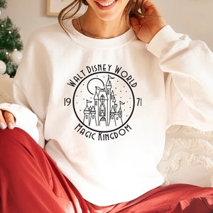 Puede incluir: Sudadera blanca con un gr&aacute;fico en blanco y negro del castillo de Cenicienta con el texto "Walt Disney World 1971 Magic Kingdom".