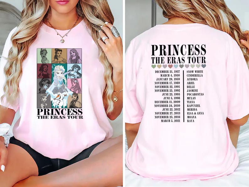 May include: Pink t-shirt with a graphic of Disney princesses and the text "Princess The Eras Tour". The back of the shirt has a list of princesses and their corresponding release dates.