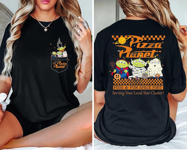 Pode incluir: Camiseta preta com um design de bolso com alien&iacute;genas de desenho animado e o texto "Pizza Planet". A parte de tr&aacute;s da camiseta exibe "Pizza Planet" em laranja, com alien&iacute;genas de desenho animado em fantasias de Halloween. O texto nas costas diz "Food & Fun Space Port."