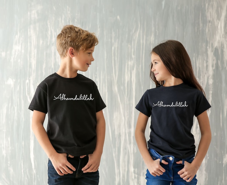 May include: Two children wearing black t-shirts with the text "Alhamdulillah" in white. The boy is wearing blue jeans and the girl is wearing blue jeans.