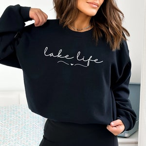May include: Black sweatshirt with the text "lake life" in white cursive lettering.