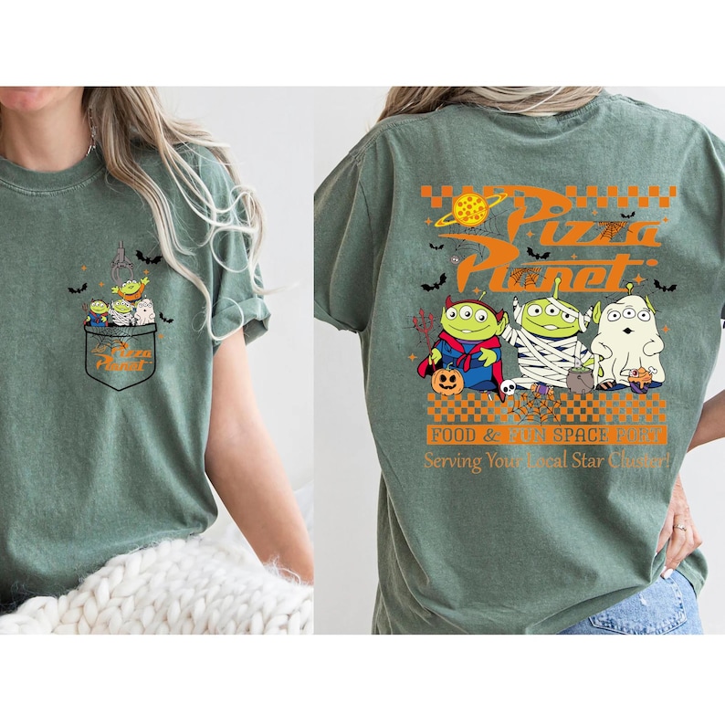 Pode incluir: Camiseta verde s&aacute;lvia com um design Pizza Planet com tema de Halloween. O bolso frontal tem um gr&aacute;fico de alien&iacute;genas. A parte de tr&aacute;s da camisa exibe o logotipo da Pizza Planet e alien&iacute;genas fantasiados, com o texto "FOOD & FUN SPACE BREW Serving Your Local Star Chaser!"