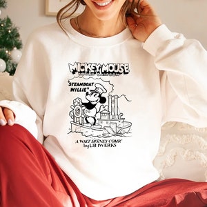 K&ouml;nnte beinhalten: Wei&szlig;es Sweatshirt mit einer Schwarzwei&szlig;illustration von Mickey Mouse als Dampfschiffkapit&auml;n. Der Text "Mickey Mouse Sound Cartoon" befindet sich &uuml;ber dem Bild und "Steamboat Willie" unter dem Bild. Der Text "A Walt Disney Comic by UB Iwerks" befindet sich am unteren Rand des Bildes.