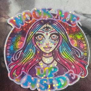May include: A holographic sticker with a colourful, psychedelic design. The sticker features a woman with a third eye and the text "Look Me Up Inside".