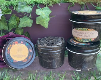 May include: Three black jars of charcoal and cocoa body scrub. The jars are labeled "CHARCOAL & COCOA BODY SCRUB".