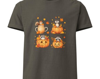 Peut inclure: T-shirt vert olive foncé avec un motif automnal fantaisiste. Le graphisme comprend quatre panneaux avec des animaux mignons : un écureuil dans une tasse, un renard sur une citrouille et deux ratons laveurs dans des lanternes, entourés de feuilles d'automne.