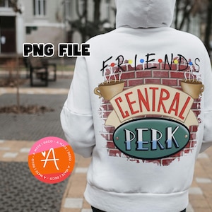 以下が含まれることがあります： 背中に「フレンズ」と「セントラルパーク」のグラフィックが入った白いパーカー。デザインはレンガの壁、コーヒーカップ、セントラルパークのロゴが特徴です。パーカーにはフードと長袖が付いています。