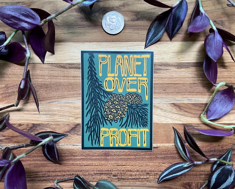 May include: A rectangular sticker with the text "PLANET OVER PROFIT" in yellow and white. The sticker features a teal background with a pine tree and pine cone design. The sticker is surrounded by purple and green plants and a coin.