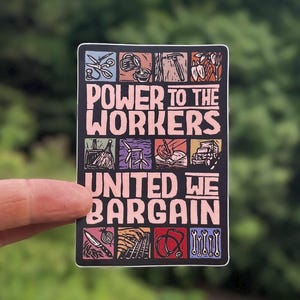 May include: A rectangular sticker with a black background featuring the text "POWER TO THE WORKERS" and "UNITED WE BARGAIN" in light pink. The design includes twelve small square illustrations of various tools and symbols representing different labor sectors.