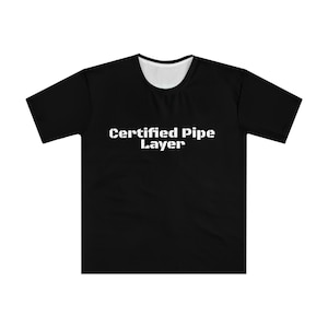 以下が含まれることがあります： 中央に白い文字で「Certified Pipe Layer」と書かれた黒いTシャツ。Tシャツはクルーネックで半袖です。襟の内側は白です。