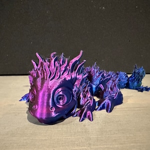 Puede incluir: Un lagarto impreso en 3D de color morado y azul con una espalda espinosa y ojos grandes.