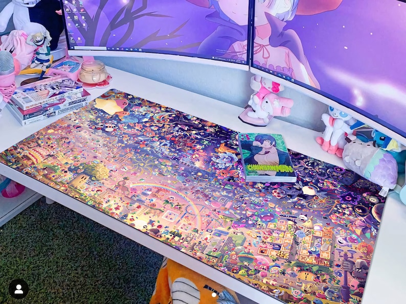 Puede incluir: Una alfombrilla de escritorio colorida con una ilustraci&oacute;n detallada de una ciudad llena de personajes de dibujos animados. La alfombrilla est&aacute; sobre un escritorio blanco con algunos libros y peluches.