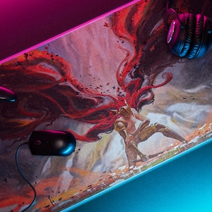 May include: A gaming mouse pad with a colorful illustration of a person with wings. The mouse pad is on a black surface with a pink and blue light reflecting on it. A black gaming controller and headphones are also on the mouse pad.