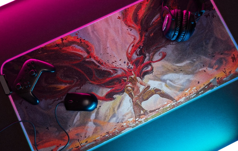 May include: A gaming mouse pad with a colorful illustration of a person with wings. The mouse pad is on a black surface with a pink and blue light reflecting on it. A black gaming controller and headphones are also on the mouse pad.
