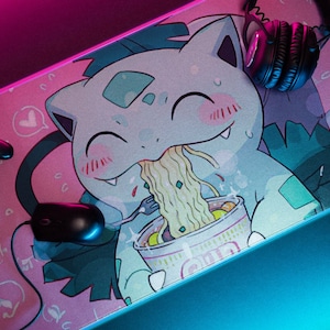 May include: A pink and blue gaming mousepad with a cartoon character eating ramen noodles. The character has a light blue body with green hair and a pink blush. The mousepad also features a pair of black headphones and a black video game controller.