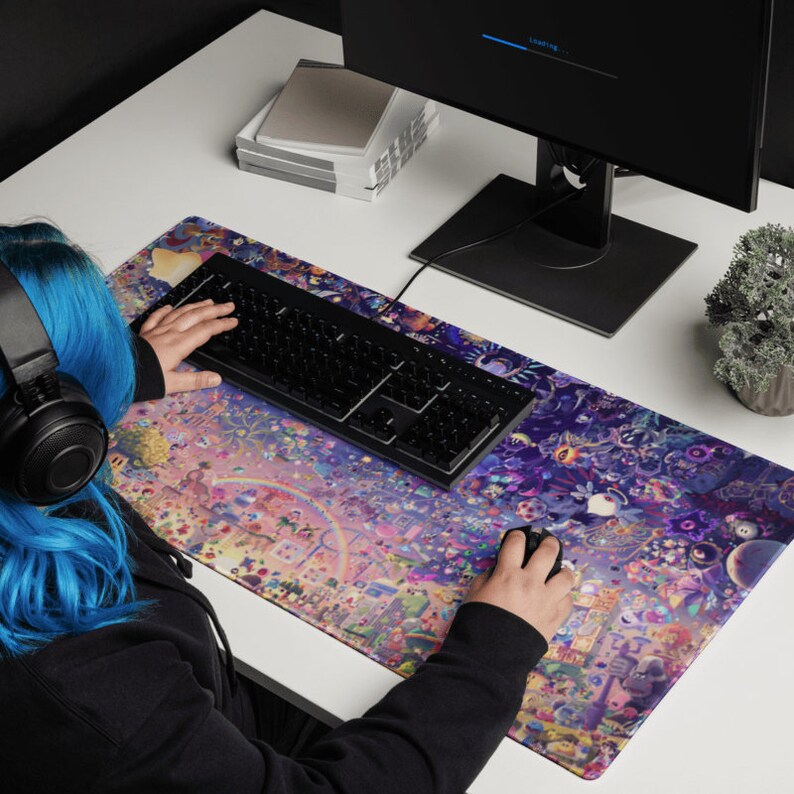 Puede incluir: Una persona usando un teclado y un rat&oacute;n negros sobre una alfombrilla de rat&oacute;n grande y colorida con un dise&ntilde;o detallado y caprichoso. La alfombrilla de rat&oacute;n presenta una variedad de personajes y objetos, incluyendo un arco&iacute;ris, estrellas y flores.