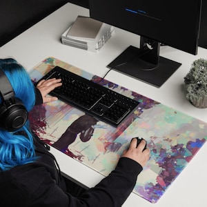 May include: A rectangular mouse mat featuring an abstract design in shades of purple, pink, and blue. A black keyboard and mouse are on the mat. The image shows a person using the keyboard and mouse. A computer monitor is in the background.