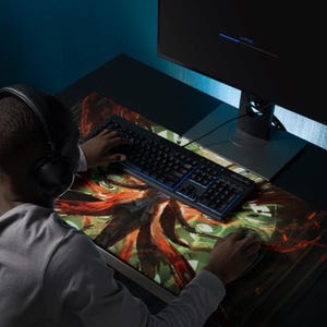 May include: A person using a keyboard and mouse on a desk with a colorful abstract design mousepad. The keyboard has blue backlighting.