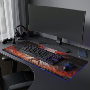 May include: A black and red gaming mouse pad with a colorful abstract design. A black keyboard with purple keys and a black gaming mouse are on the mouse pad. A black computer monitor is in the background.
