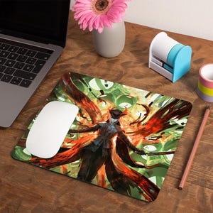 May include: A colorful mousepad with a graphic of a person in a black coat and hat standing in a field of red and green. The person is surrounded by a swirling pattern of red and green.