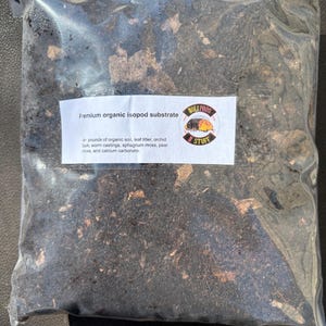 May include: A clear plastic bag filled with a dark brown organic isopod substrate. The bag has a white label that reads "Premium organic isopod substrate" and lists the ingredients: organic soil, leaf litter, orchid bark, worm castings, sphagnum moss, peat moss, and calcium carbonate.