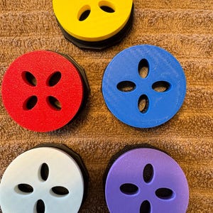 May include: Five round, colorful, foam discs with a black base and four oval cutouts. The discs are yellow, red, blue, white, and purple.