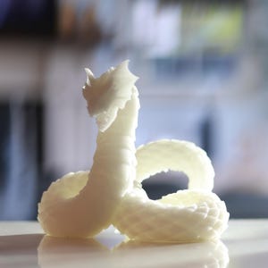 Puede incluir: Un modelo de serpiente en espiral impreso en 3D en blanco.