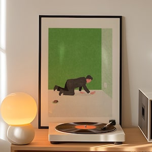 May include: A white turntable with a black vinyl record playing, beside a framed art print with a green background and a figure in a suit. A white and cream globe lamp sits on a wooden shelf.