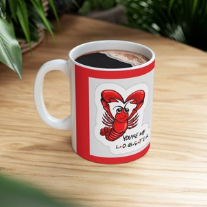 May include: White ceramic mug with a red rim and a red background. The mug features a cartoon lobster with the text "You're my lobster" on it.