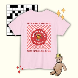 May include: Pink t-shirt with a red and white checkered pattern and a logo that says "Dough Bricks by the Sea". The logo features a cartoon pizza slice with a face. The text "Let's make a pizza pie that is 120% all of us" is printed on the shirt.