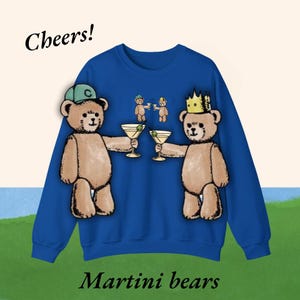 May include: A blue sweatshirt with a graphic of two teddy bears wearing hats and holding martini glasses. The text "Cheers!" is at the top and "Martini bears" is at the bottom of the sweatshirt.