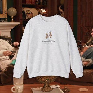 May include: A heather grey sweatshirt with a graphic of two teddy bears wearing hats. The text "I AM ADDICTED to these two bears." is printed below the bears.