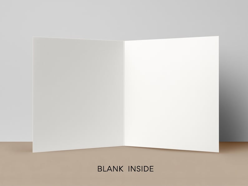 May include: An open, blank greeting card with a white interior. The card is displayed on a tan surface against a neutral background. The words "BLANK INSIDE" are printed at the bottom of the card.