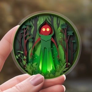 May include: A papercraft scene depicting a green humanoid figure with glowing red eyes standing in a forest. The figure is surrounded by trees and foliage, creating a mystical and otherworldly atmosphere.