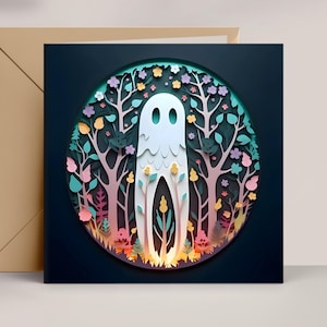 May include: A square card with a paper-cut design of a white ghost in a forest setting, surrounded by trees, flowers, and foliage in shades of green, pink, and yellow. A brown envelope is next to the card.