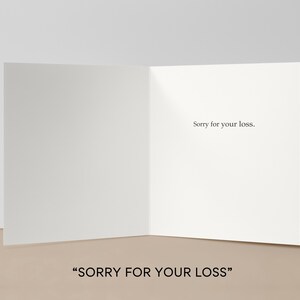 May include: A blank, folded greeting card with the text "Sorry for your loss." printed in black. The card is open, revealing the inside, and is set against a neutral background. The words "SORRY FOR YOUR LOSS" are at the bottom.