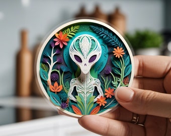 May include: A papercraft sculpture of an alien with a detailed face and intricate floral patterns surrounding it. The alien is white with purple eyes and is surrounded by green, blue, orange, and purple flowers.