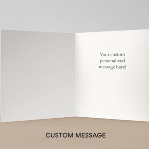 May include: An open, blank greeting card with the text "Your custom personalized message here!" on the right side. The words "CUSTOM MESSAGE" are at the bottom. The card is white and sits on a tan surface.