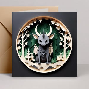 May include: A square greeting card with a paper-cut design featuring a gray dragon in a forest scene. The dragon has horns and wings, set against a green and white backdrop. A tan envelope is on the left.