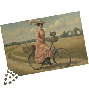 May include: A vintage jigsaw puzzle showing a woman in a pink dress cycling on a dirt track. A small dog is in the front basket. The background features a field, a church, and a blue sky.