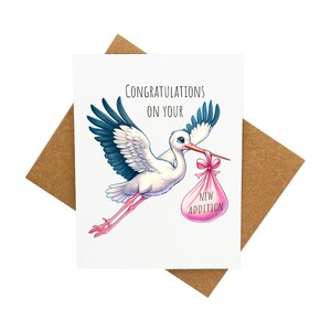 Carte pour nouveau-né avec une cigogne portant un sac rose [Légende : Félicitations pour votre nouvel ajout] - Livrée avec une enveloppe