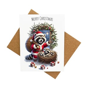 Carte de voeux de père Noël raton laveur livrant des cadeaux à des bébés ratons laveurs [Légende : Joyeux Noël] - Livrée avec une enveloppe