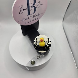 May include: A white ceramic mug with a black handle and the text "But First, Coffee" in a bold, black font. The mug is set against a blurred background, suggesting a cozy setting.